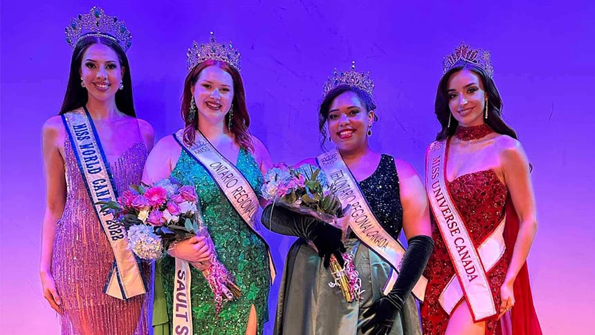Four young women wearing gowns, crowns and sashes pose and smile.